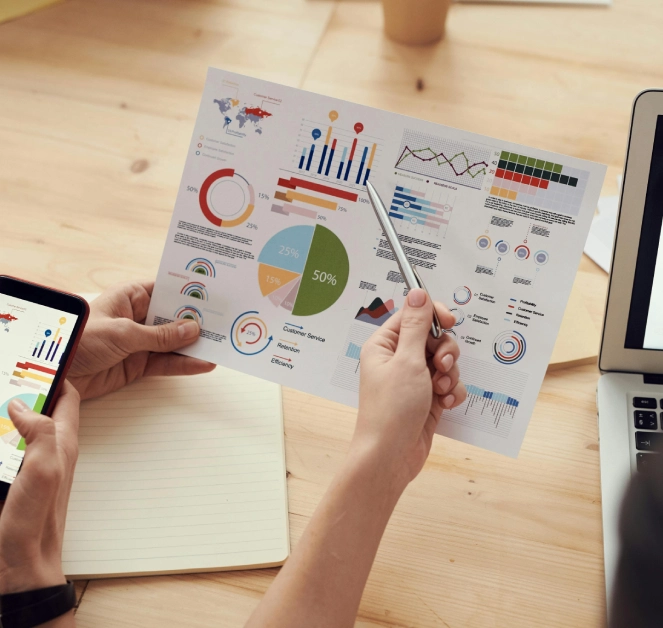 Person reviewing infographic charts on printed business data sheets