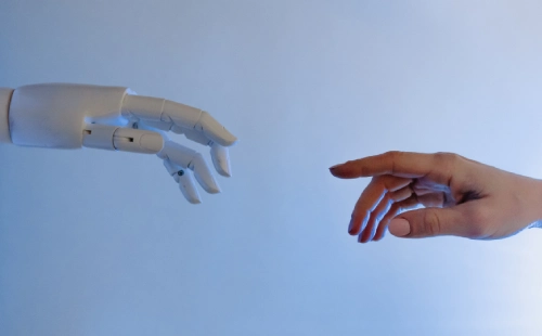 Robotic hand and human hand stretching to connect against blue background