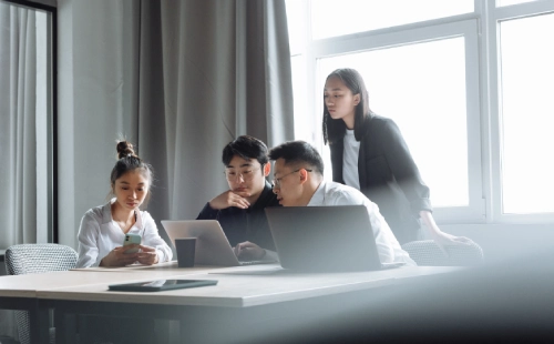 Team meeting in bright office discussing capacity, laptops and devices on desk
