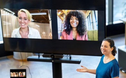 In-person presenter interacting with participants on screen in virtual meeting session