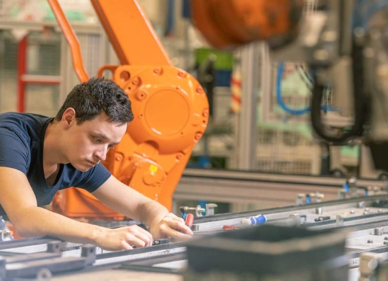 Male engineer working with industrial automation equipment, representing advanced packaging innovation in a factory setting.