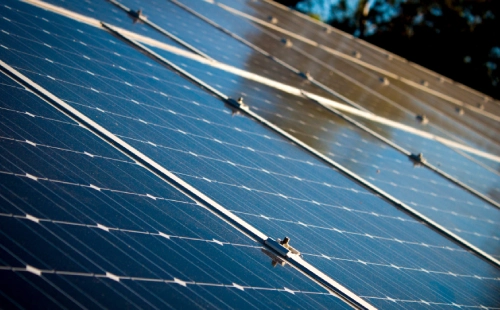 Sunlight reflecting off multiple blue solar panels for sustainable energy generation